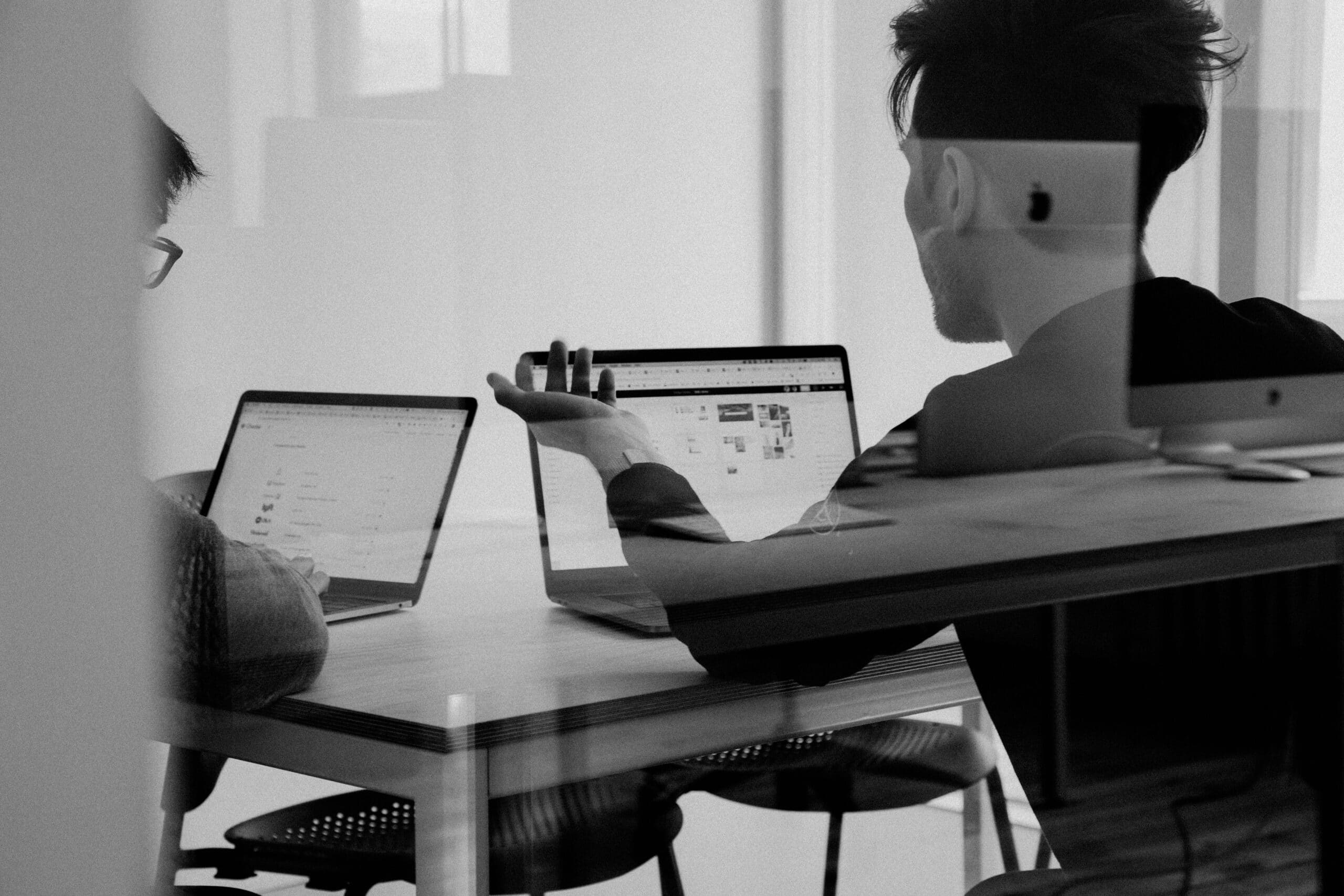Schwarz weiss Bild von zwei Personen die am Laptop arbeiten