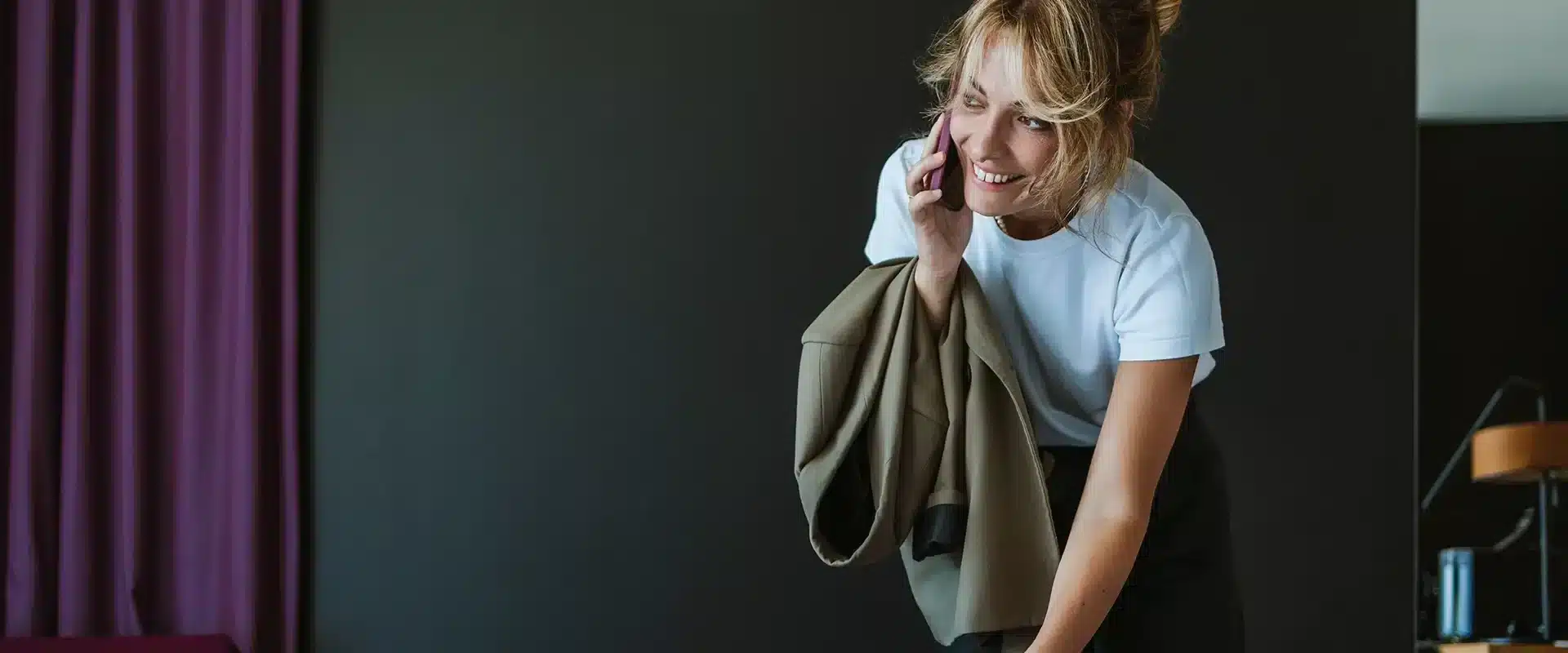 Frau telefoniert im Hotelzimmer und packt dabei ihre Koffer