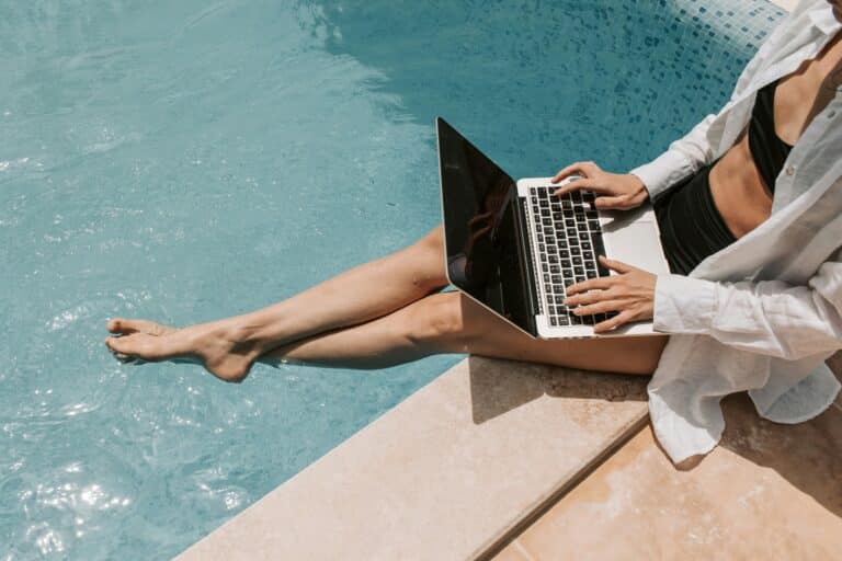 Frau mit Laptop am Pool