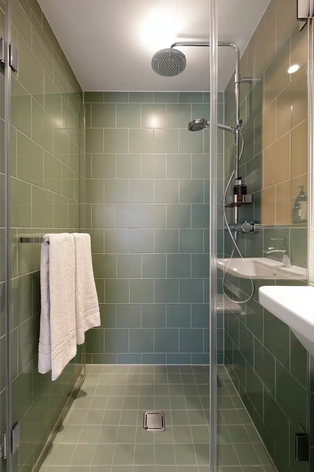 Dusche mit grünen Wandfliesen und Glaswand